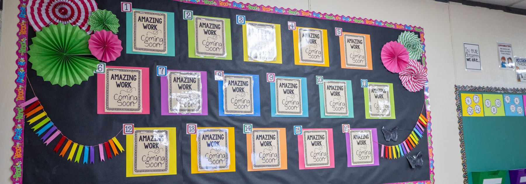 A lively classroom adorned with bright paper fans and a bulletin board showcasing student work and announcements.