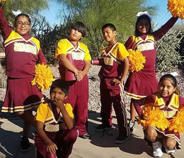 Six male and female students posing in their cheerleading uniforms.  